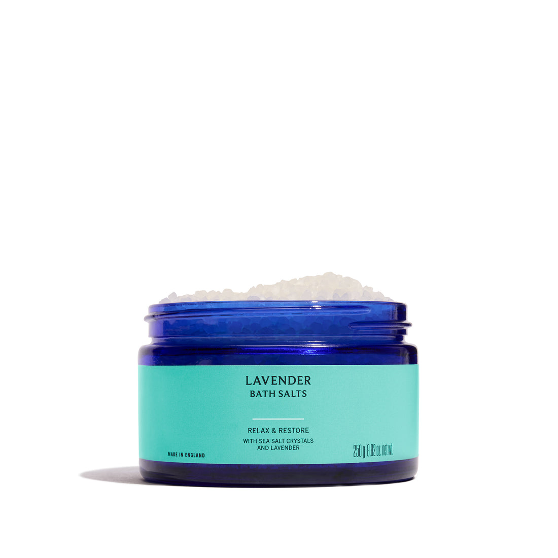 A jar of Lavender Bath Salts in a dark blue jar with a black lid and a light turquoise label, set against a plain white background.