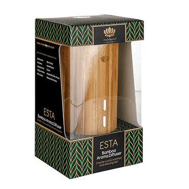 A bamboo aroma diffuser in its original retail packaging, featuring a clear window that displays the light brown bamboo cylinder, with a black and green geometric patterned box.